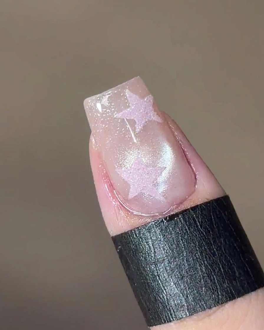 Una herramienta magnética sostenida sobre la uña, haciendo que las partículas del gel formen una cuenta de vidrio.