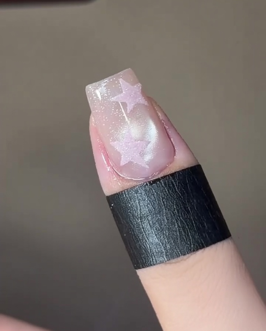 La uña bajo una mini lámpara LED siendo curada tras fijar el efecto ojo de gato.