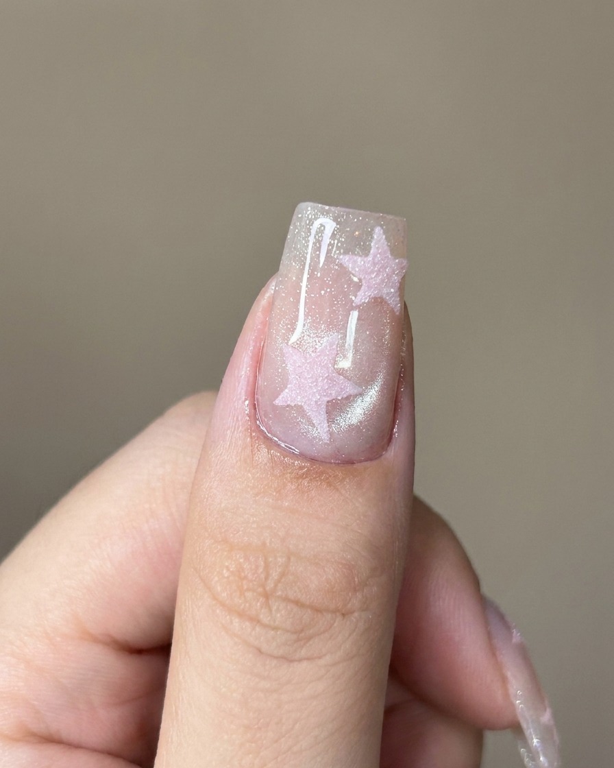 Un pincel aplicando un top coat transparente sobre la uña brillante con efecto ojo de gato.