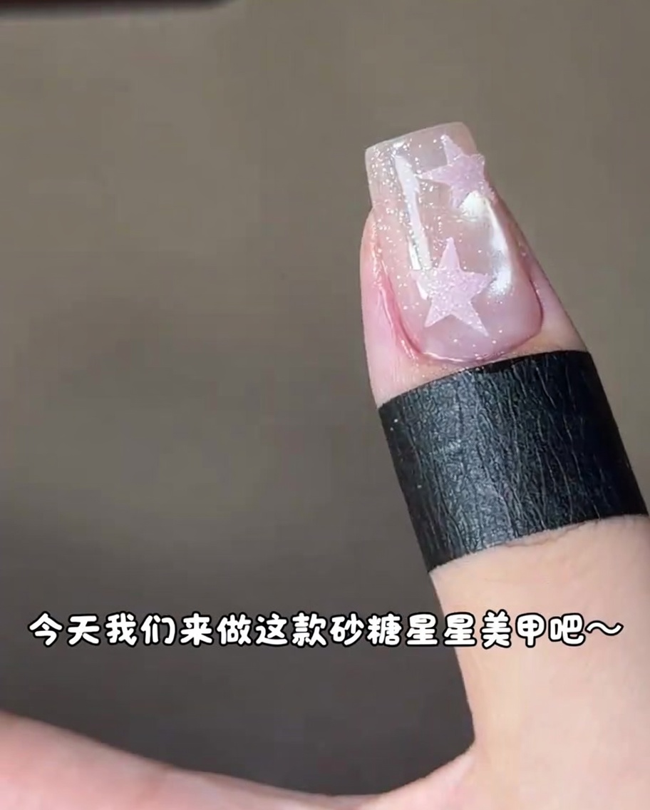 Una uña con un diseño de estrella rosa curándose bajo una lámpara de uñas UV.