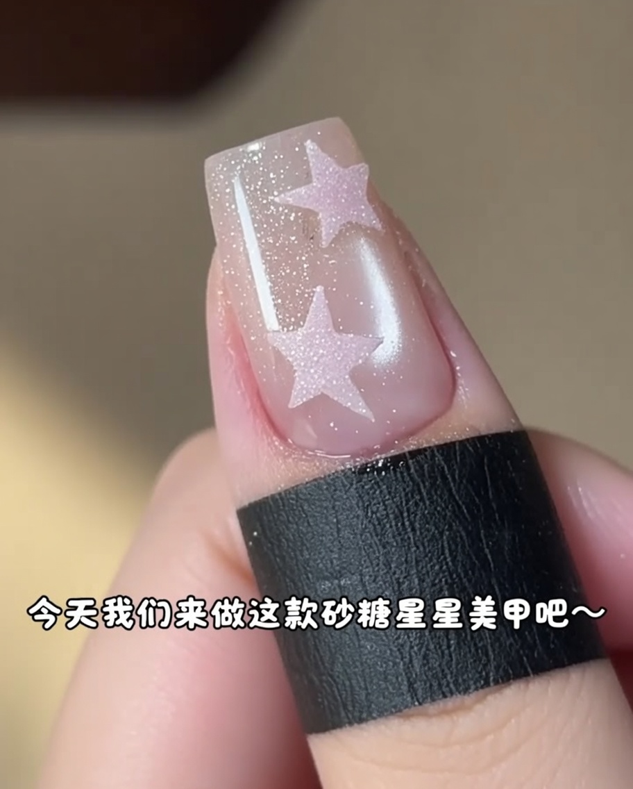 Un pincel pequeño aplicando gel rosa dentro de una pegatina de estrella en una uña.