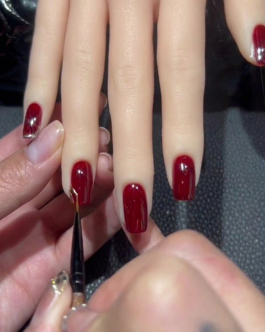 Un pincel liner fino tomando una pequeña cantidad de esmalte de gel denso con glitter oro rosa.