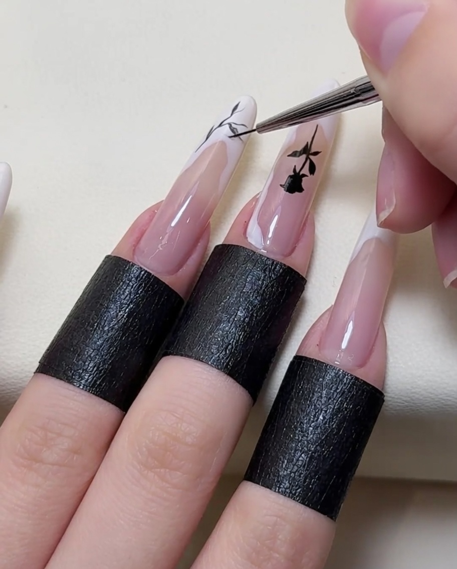 Primer plano de un pincel añadiendo detalles intrincados de ramas al diseño de uñas.