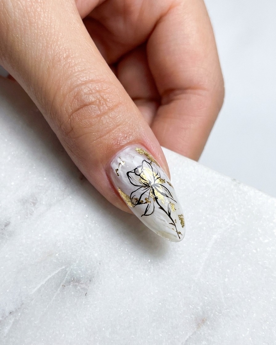 Primer plano de un pincel liner fino pintando un pétalo dorado metálico curvado en la parte superior izquierda de un diseño de rosa.