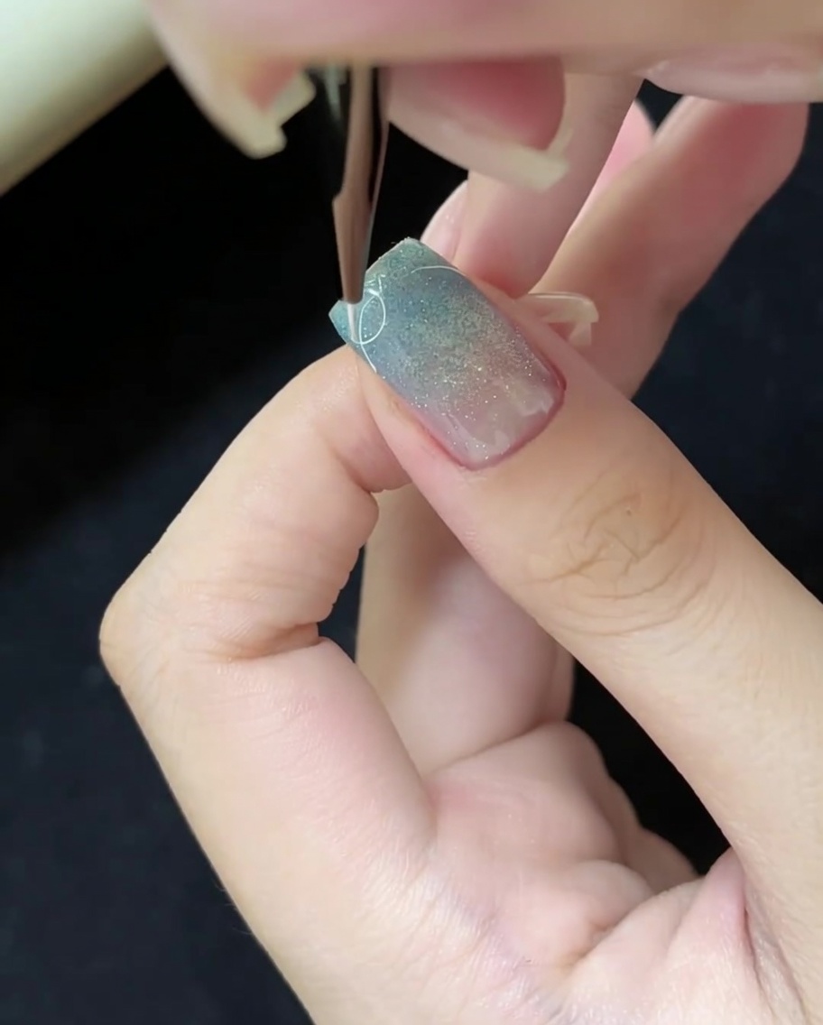 Usando un pincel liner fino para dibujar líneas blancas finas en la superficie de la uña.