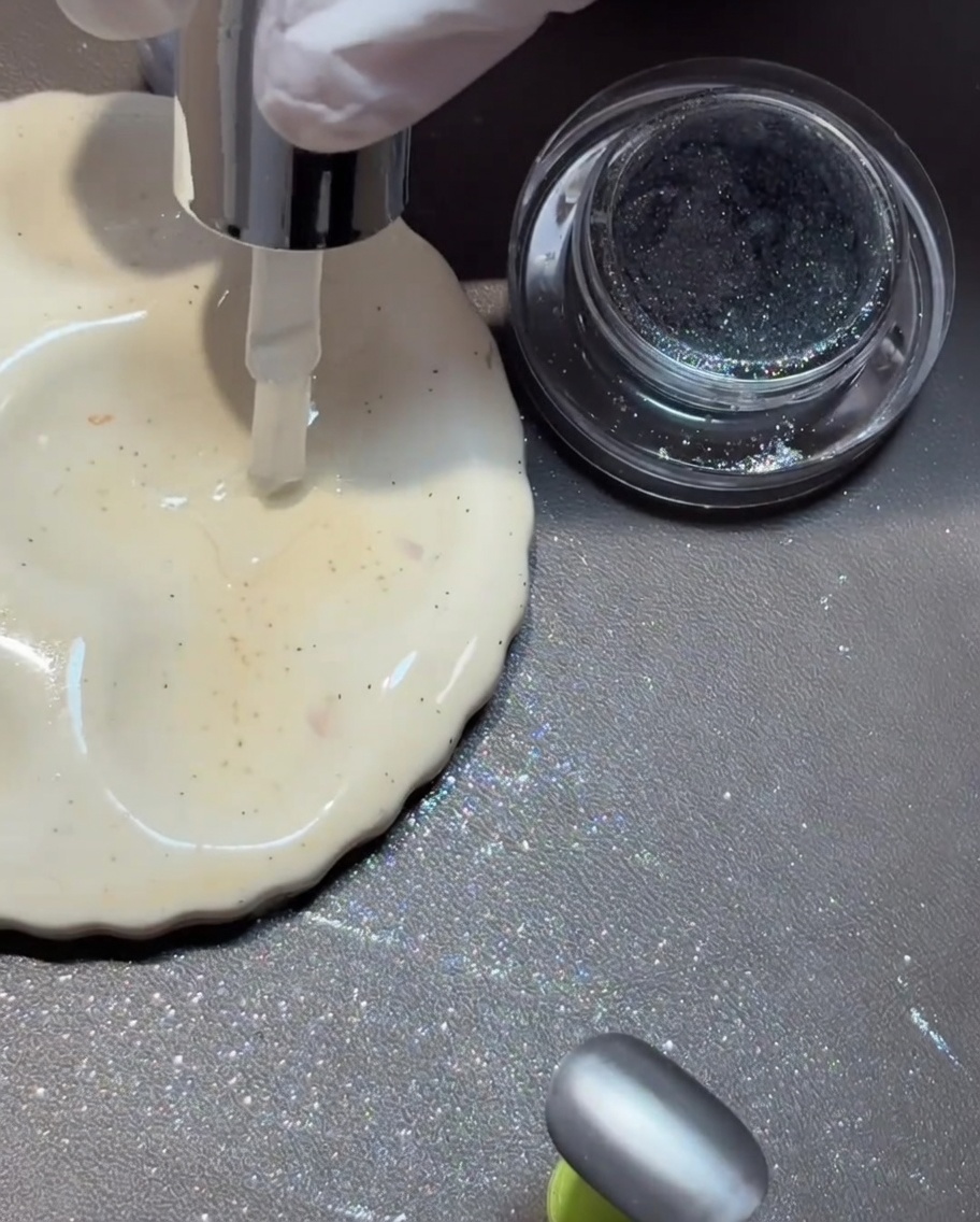 Un pincel fino dibujando un diseño con top coat brillante sobre una superficie de uña mate.