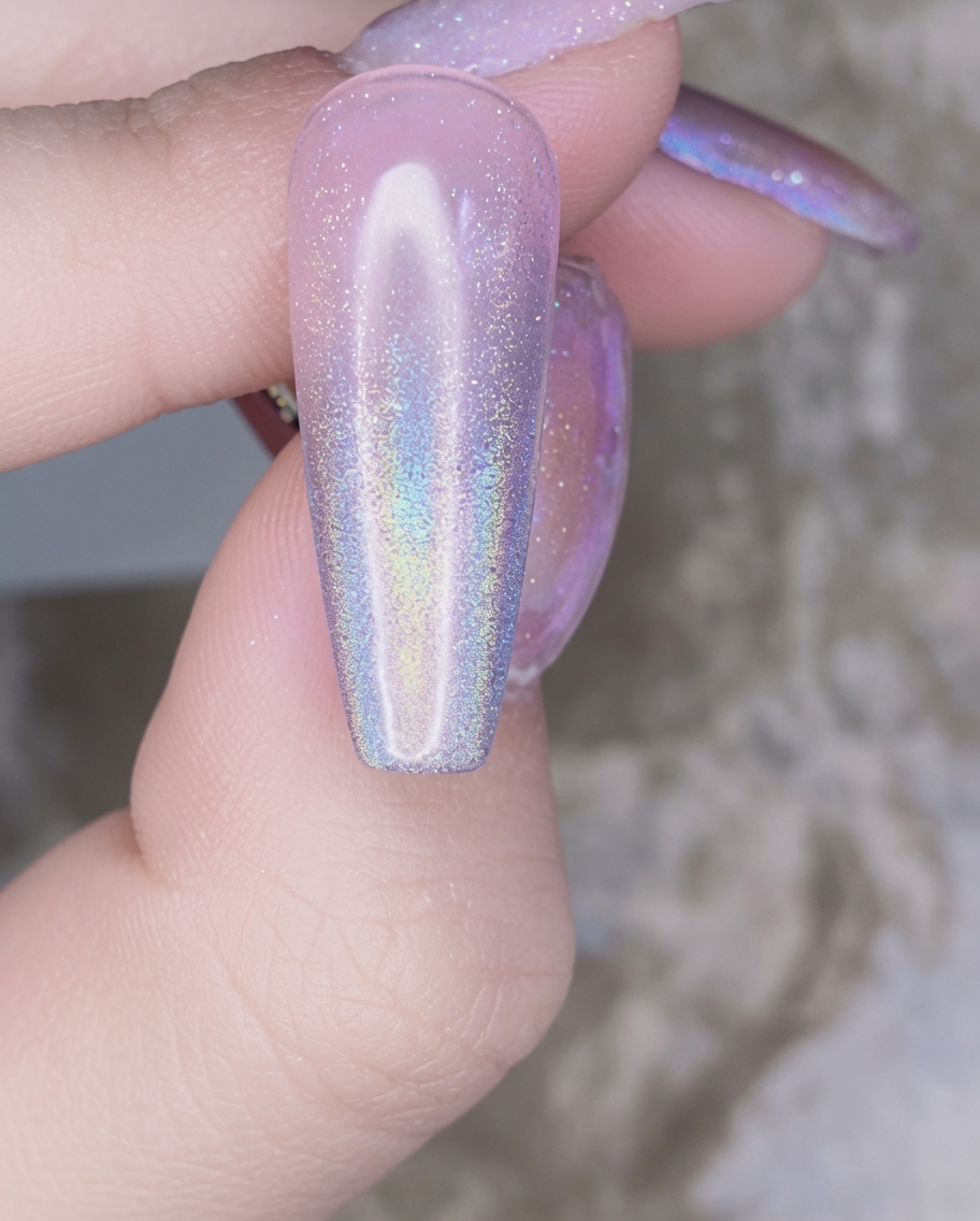 Un pincel de uñas aplicando una capa transparente de gel de refuerzo sobre la uña decorada con cromo.