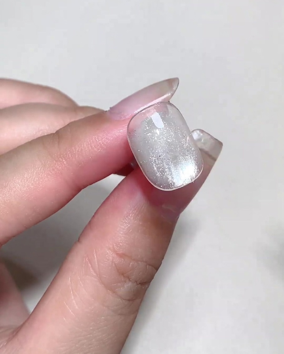 Líquido blooming colorido siendo punteado sobre una uña con blooming gel húmedo para formar burbujas.