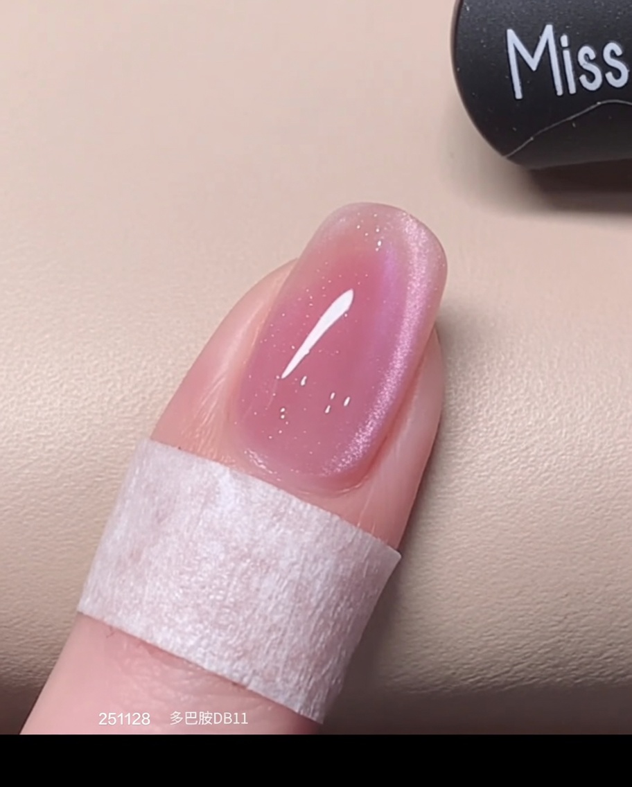 Un pincel aplicando una capa fresca y húmeda de esmalte cat eye rosa sobre la base previamente curada.