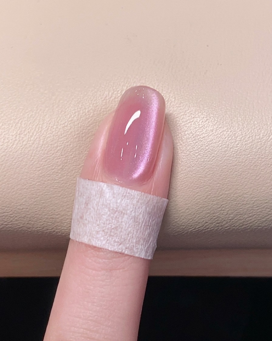 Una mano descansando dentro de una lámpara de uñas UV/LED encendida, curando la capa final.