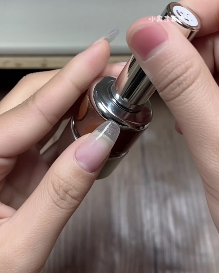 Una mano usando pinzas para seleccionar una pegatina curva para punta francesa de una hoja de guías blanca.