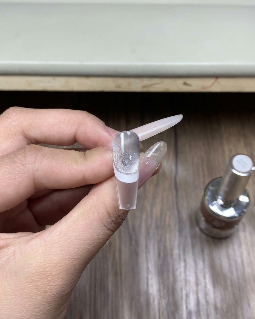 Primer plano de un pequeño frasco de vidrio de top coat especializado para cromo sobre una superficie de madera.