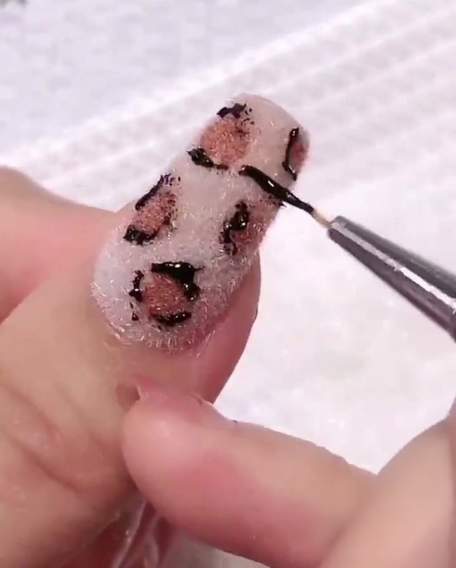 Algodón limpiando suavemente la superficie de la uña, quitando residuos de gel negro alrededor del diseño.