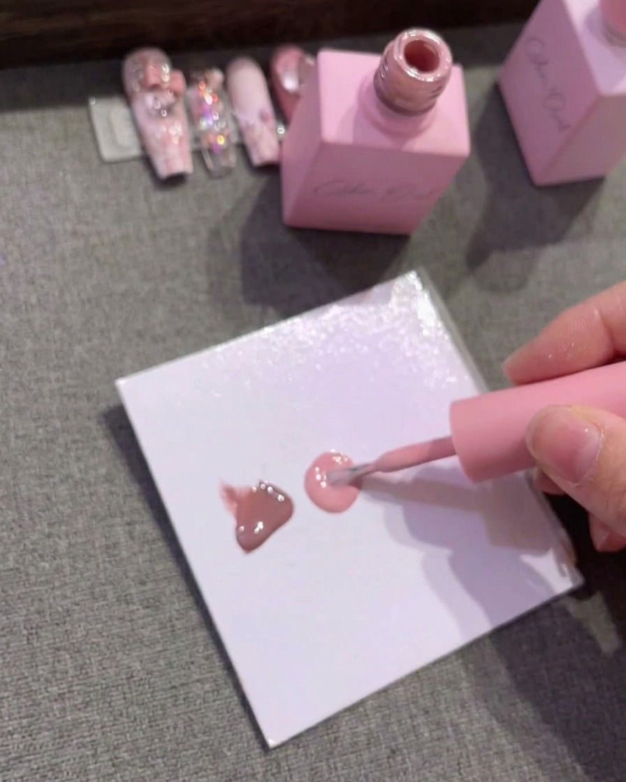 Papel de paleta mostrando tres gotas distintas de esmalte en gel en marrón, rosa medio y rosa claro.