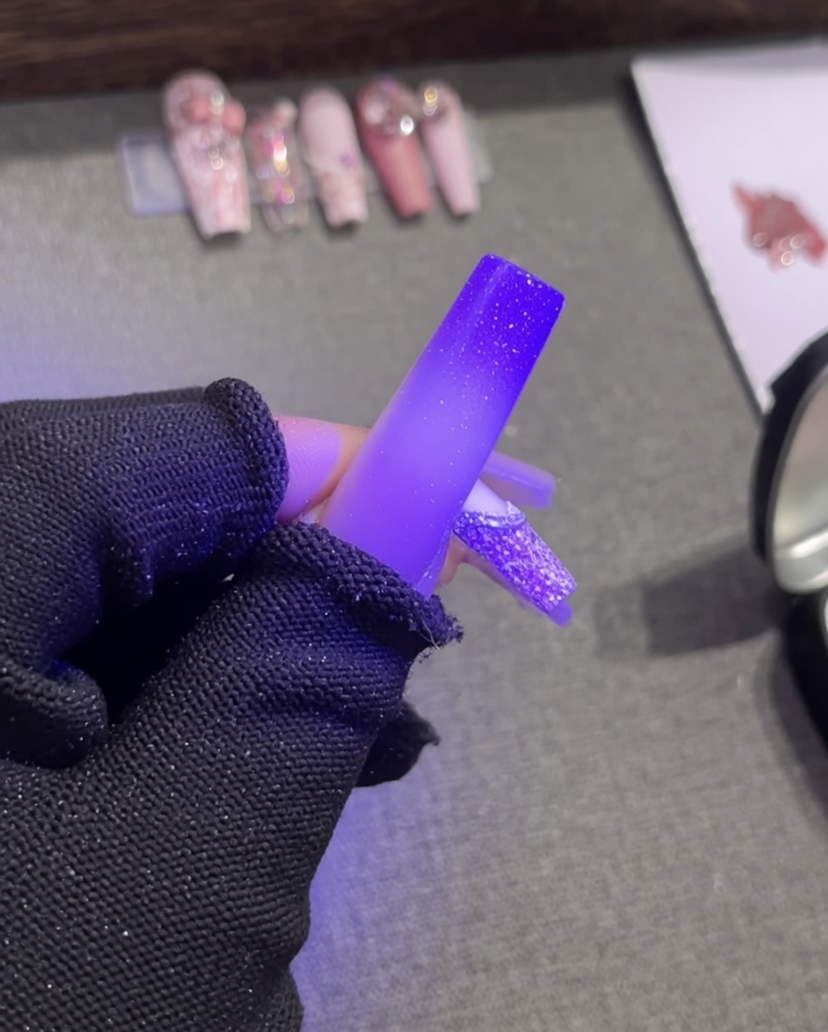 Pinzas colocando una pequeña y elegante perla blanca sobre el contorno de gel relieve blanco húmedo de una punta francesa.