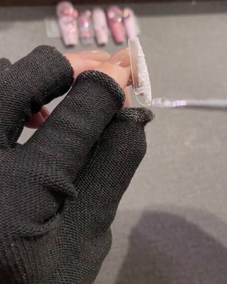 Un pincel extendiendo gel relieve blanco texturizado sobre un nuevo tip de uña transparente para crear una base de cobertura completa.
