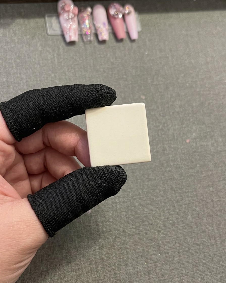 Un primer plano de un tip de uña siendo pintado con líneas de gel gruesas verticales rosas y marrones usando un pincel liner fino.