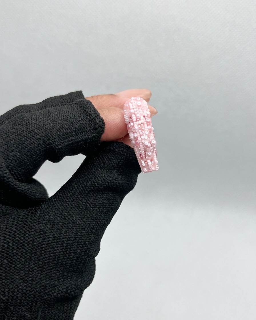 Un pincel aplicando un gel base transparente y brillante a un tip de uña de plástico transparente sin pintar.