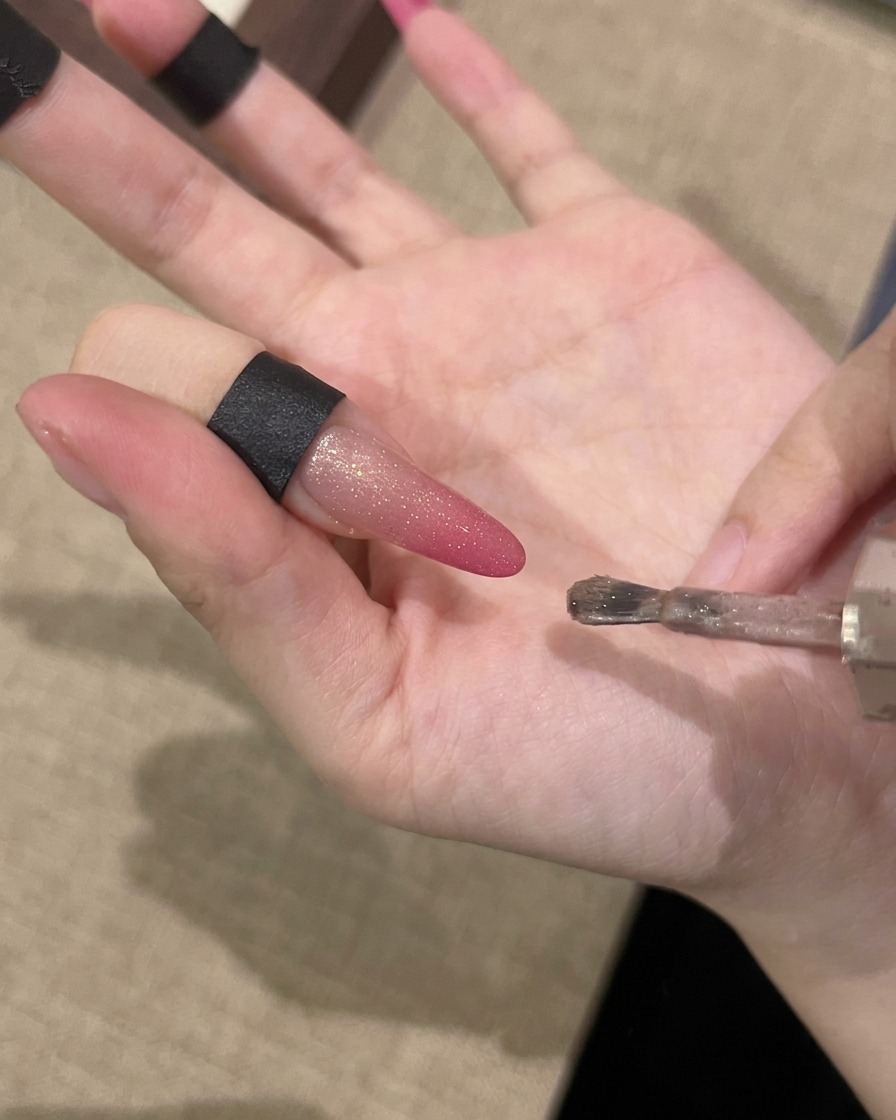 Una mano sosteniendo un imán paralelo a la uña para atraer las partículas magnéticas.