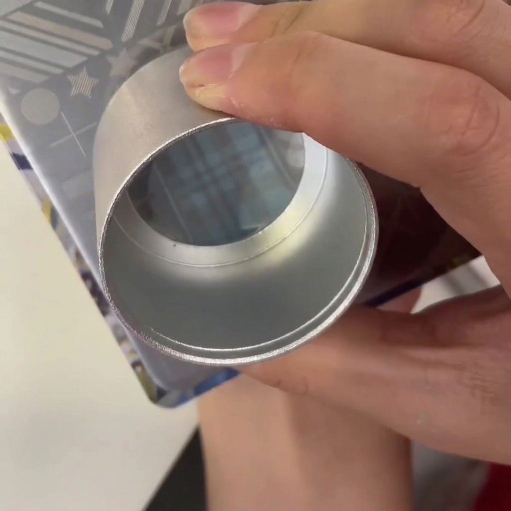 Un raspador de plástico arrastrándose a través de una placa de estampado de metal con esmalte azul en el diseño grabado.