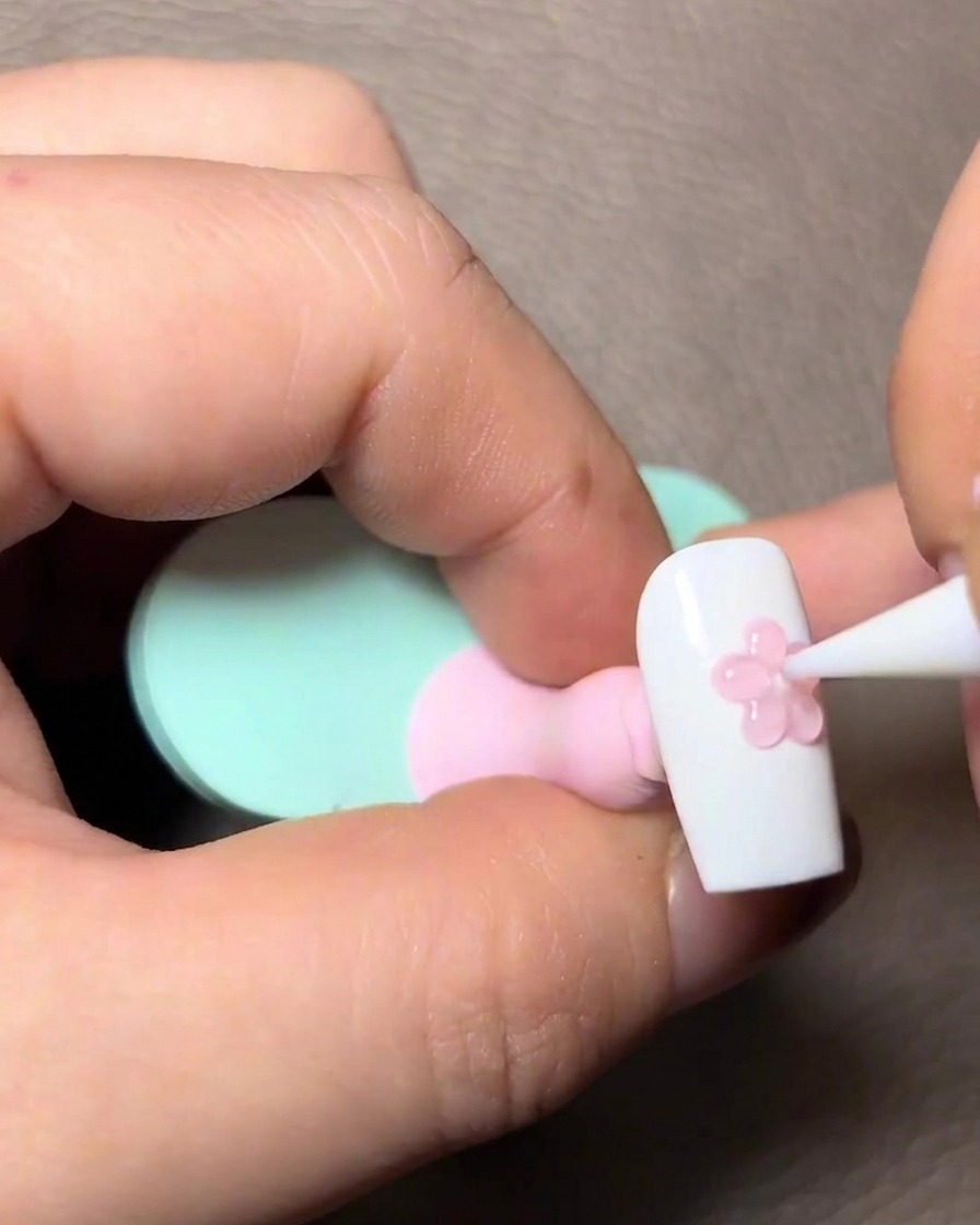 Aplicando una capa de gel rosa traslúcido sobre los detalles esculpidos en 3D.