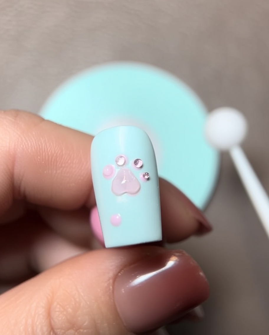 Primer plano de un pincel añadiendo una gota de gel de escultura sobre el diseño de la patita.