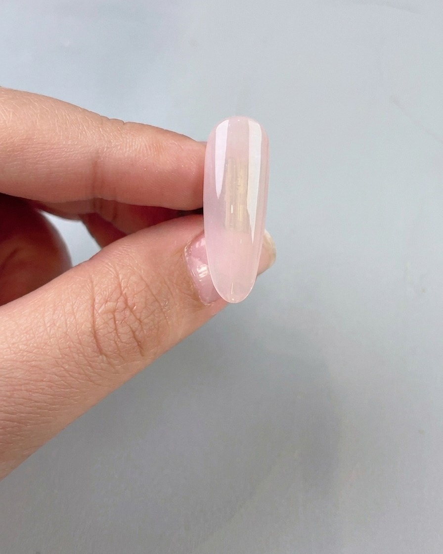 Una base de gel jade clara y ligeramente lechosa siendo aplicada sobre una uña natural.