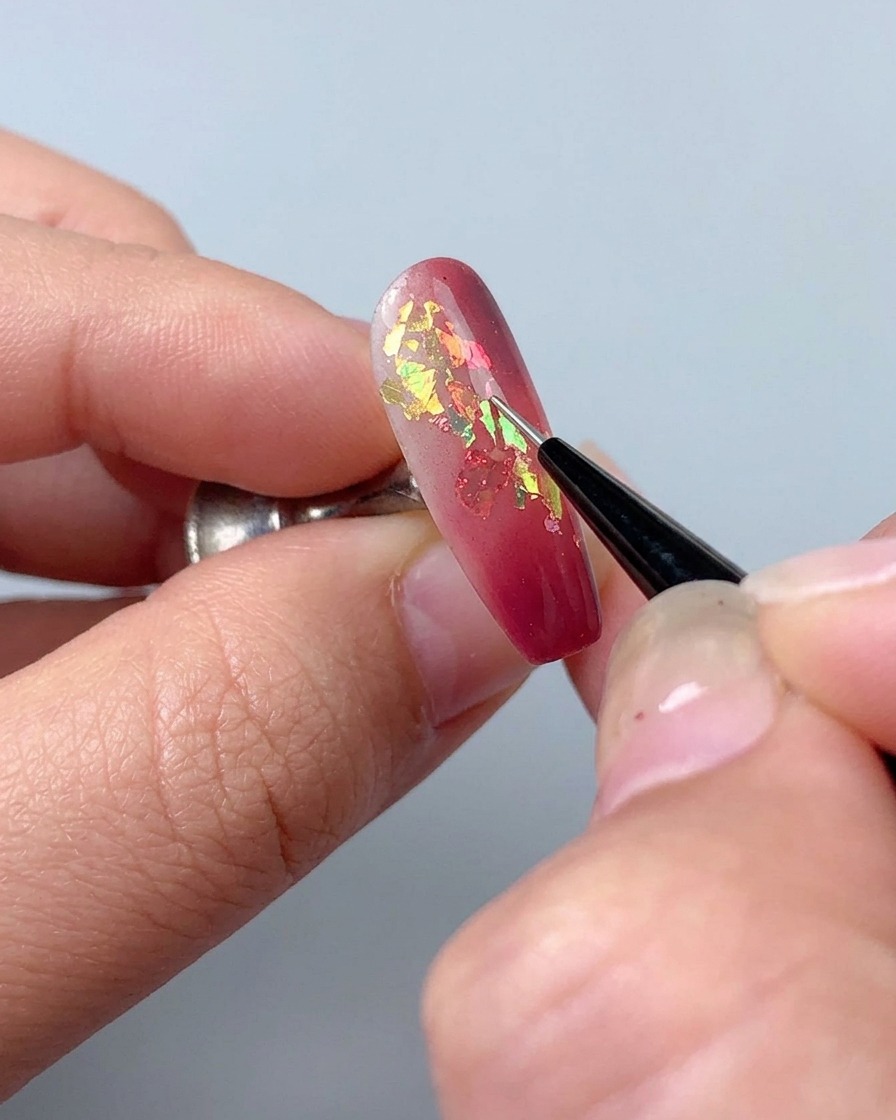 Un pincel delineador usado para dibujar líneas decorativas finas con gel de escultura sobre una uña.