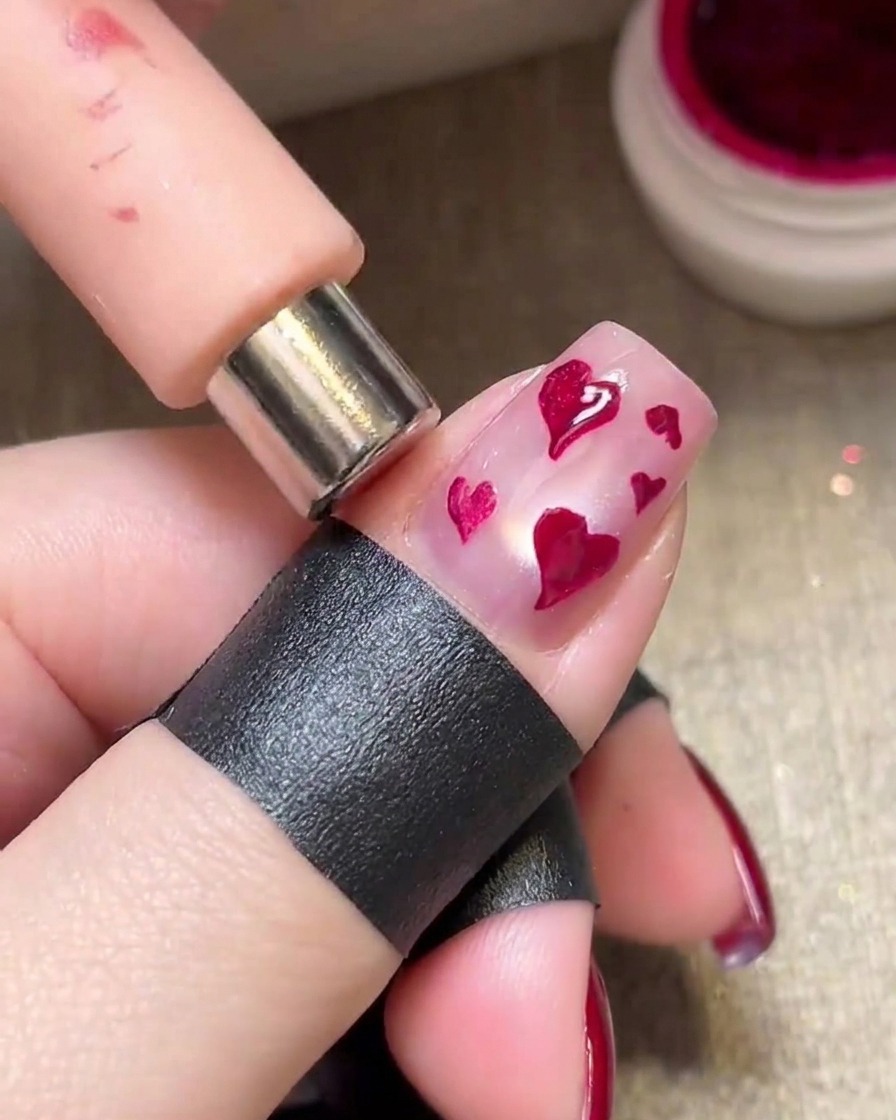 Un imán sostenido sobre corazones magenta húmedos para crear un efecto metálico brillante.