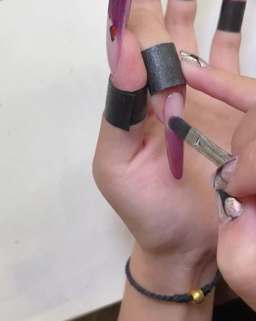 Un pincel siendo utilizado para dar forma y suavizar los bordes de la punta francesa de gel ojo de gato.
