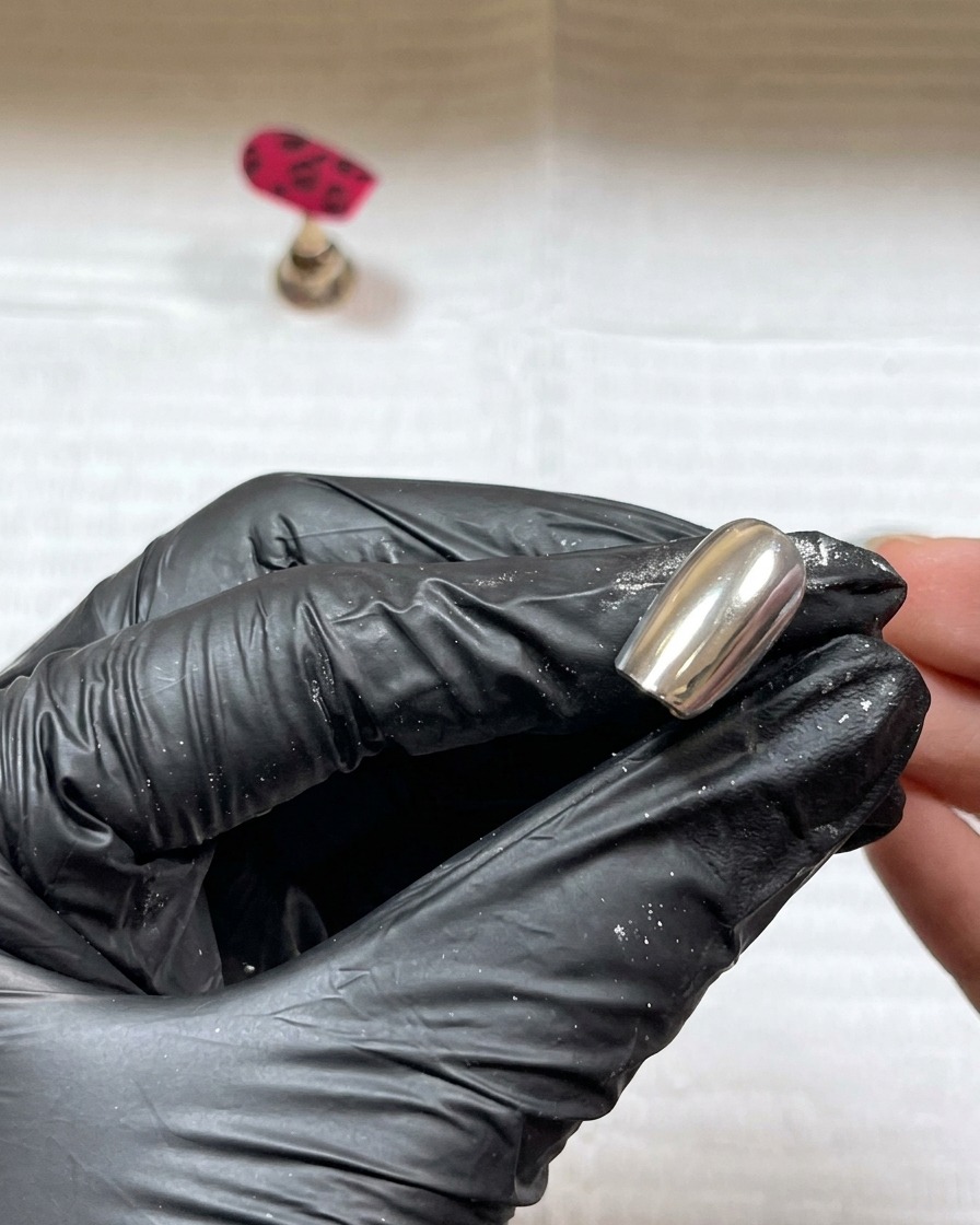 Polvo acrílico siendo espolvoreado sobre detalles de gel negro húmedo.