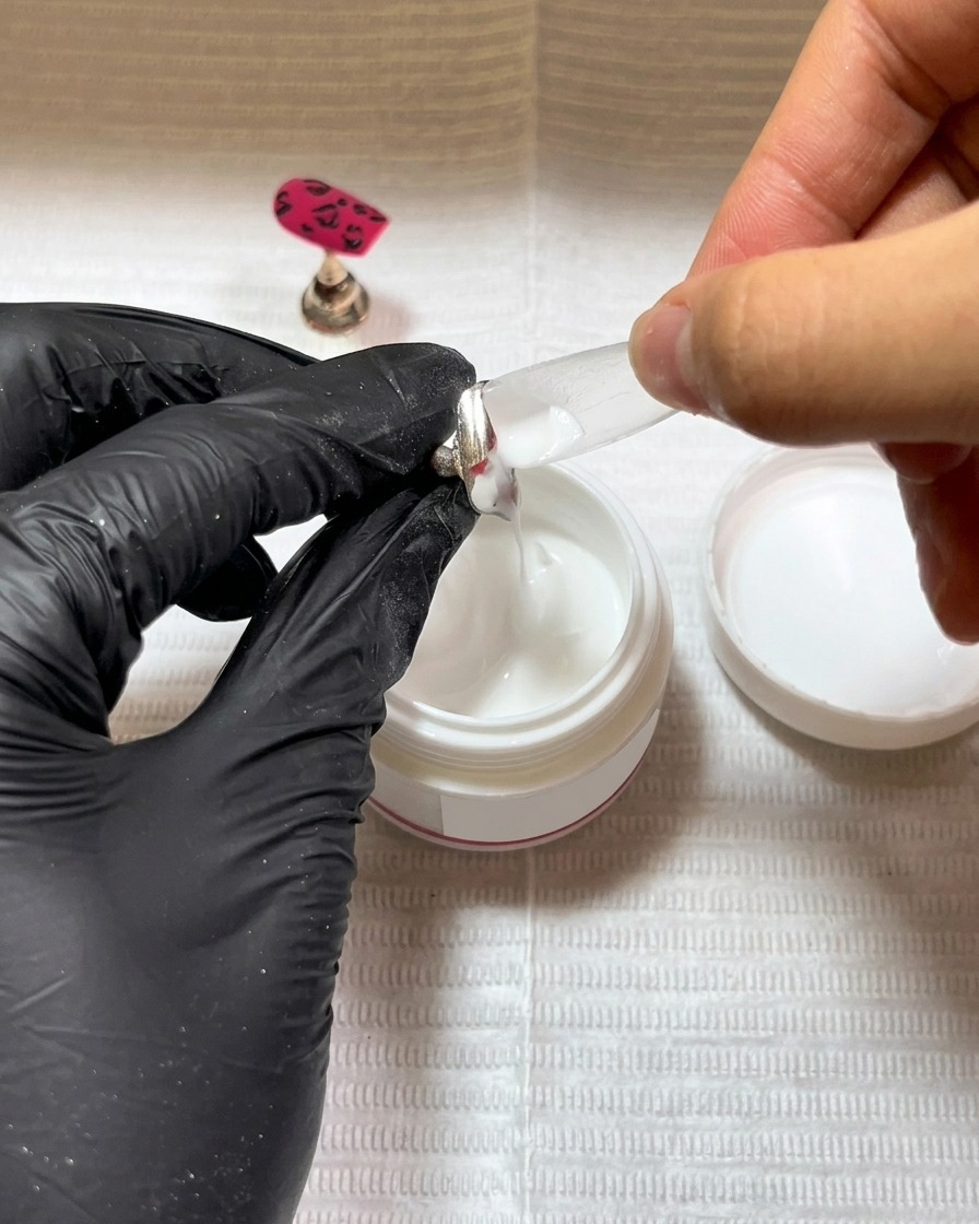 Pincel aplicando base de gel negra en un tip nuevo.