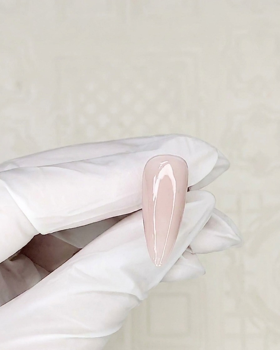Primer plano de un pincel de detalle tomando esmalte en gel blanco de un recipiente.