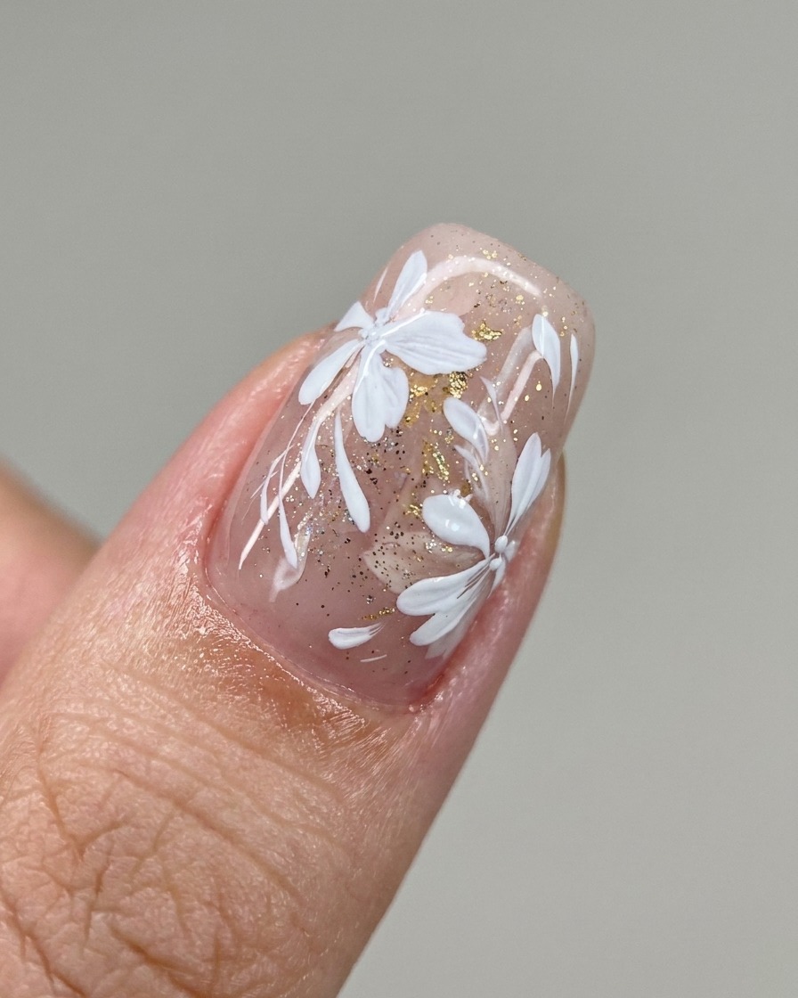 Un pincel aplicando una franja diagonal de esmalte de gel blanco lechoso sobre una uña.