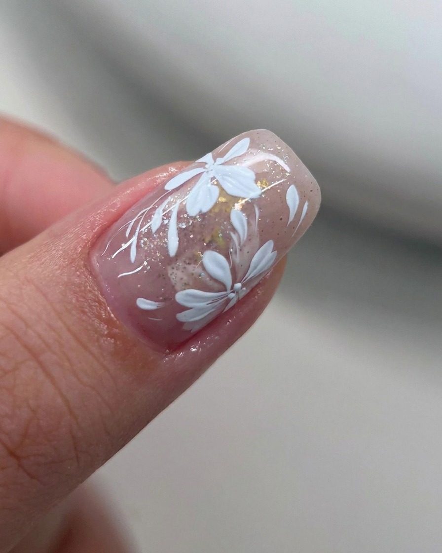 Un pincel plano suavizando el borde del esmalte de gel blanco en una uña.