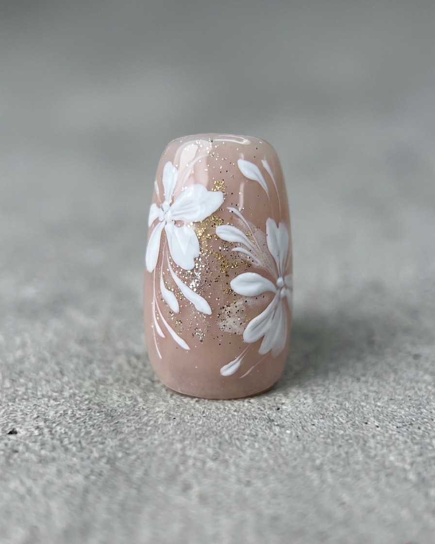 Un pincel liner fino dibujando líneas blancas curvas y delgadas sobre una uña con arte floral y dorado terminado.