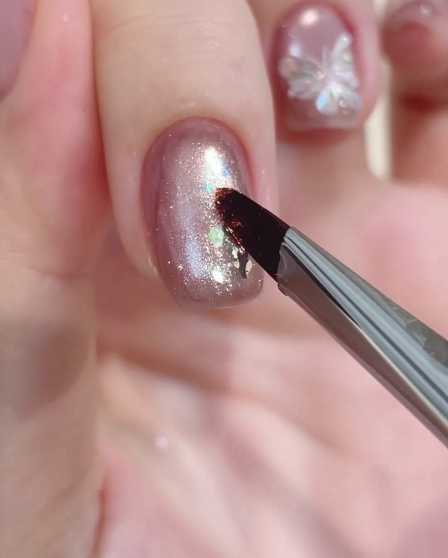 Un pincel de nail art depositando un pequeño punto de gel blanco para comenzar el diseño floral.
