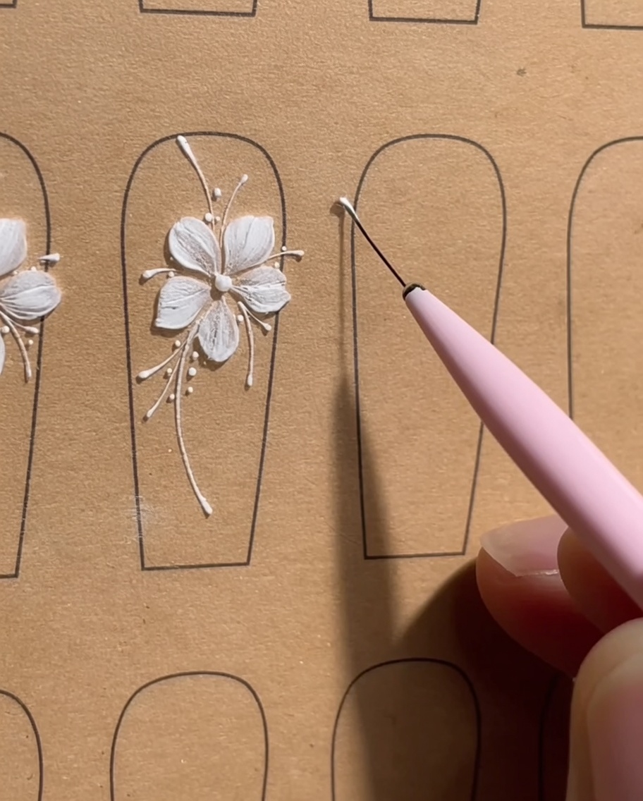 Primer plano de un tip de uña que muestra cinco puntos precisos de gel blanco dispuestos en un pequeño círculo, actuando como guía para una flor de cinco pétalos.