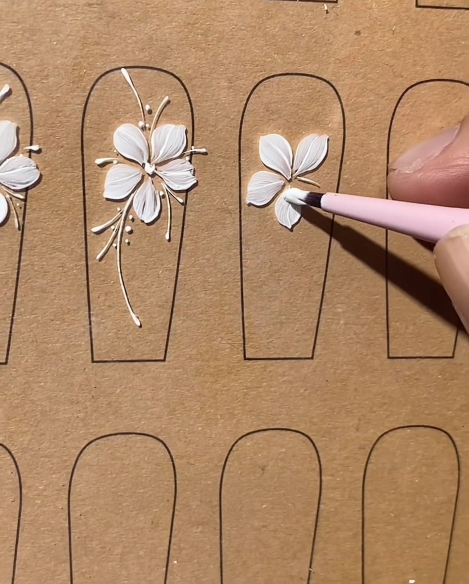 Un pincel plano terminando el quinto y último pétalo de gel blanco para completar la forma de la flor.