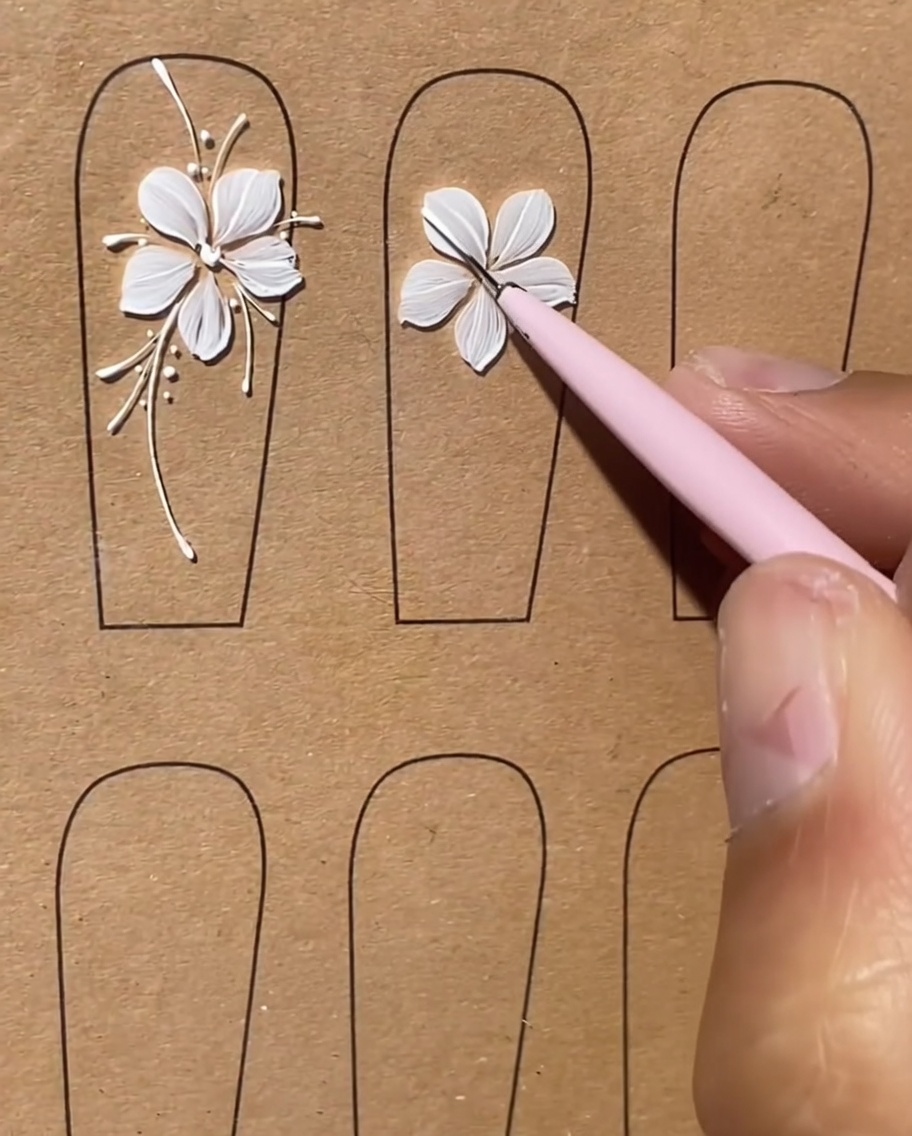 Una uña con un diseño floral blanco que presenta largas y finas líneas blancas que se extienden hacia afuera como tallos.