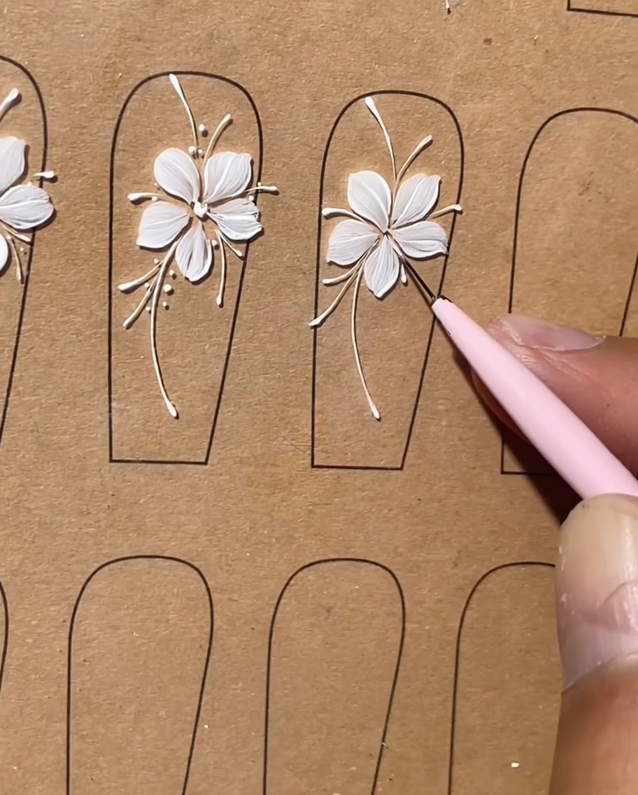 Una toma de detalle que muestra pequeños puntos blancos siendo aplicados como realces a lo largo de las líneas de un diseño floral.