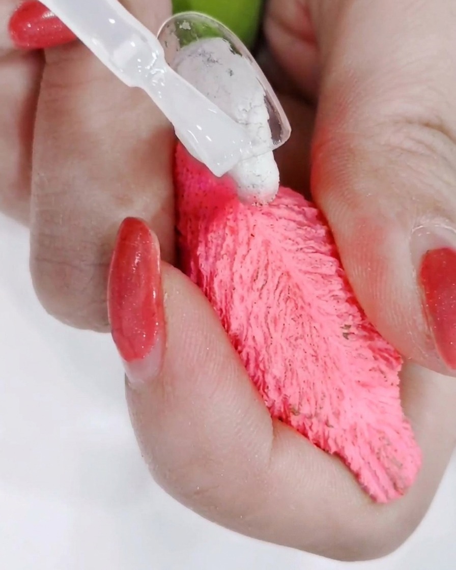 Una mano posicionada bajo una lámpara de uñas profesional con la luz curando el top coat recién aplicado.