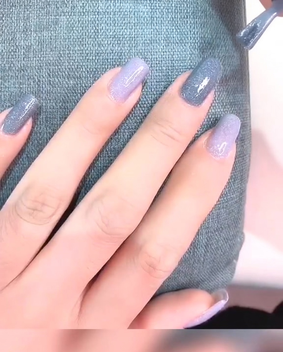 Primer plano de una uña con dos capas de esmalte de gel gris, con un aspecto opaco y liso.