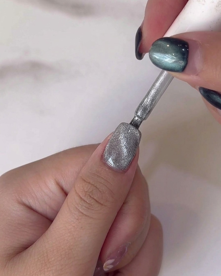 Un pincel fino añadiendo pequeños detalles de hojas verdes sobre los tallos pintados anteriormente.