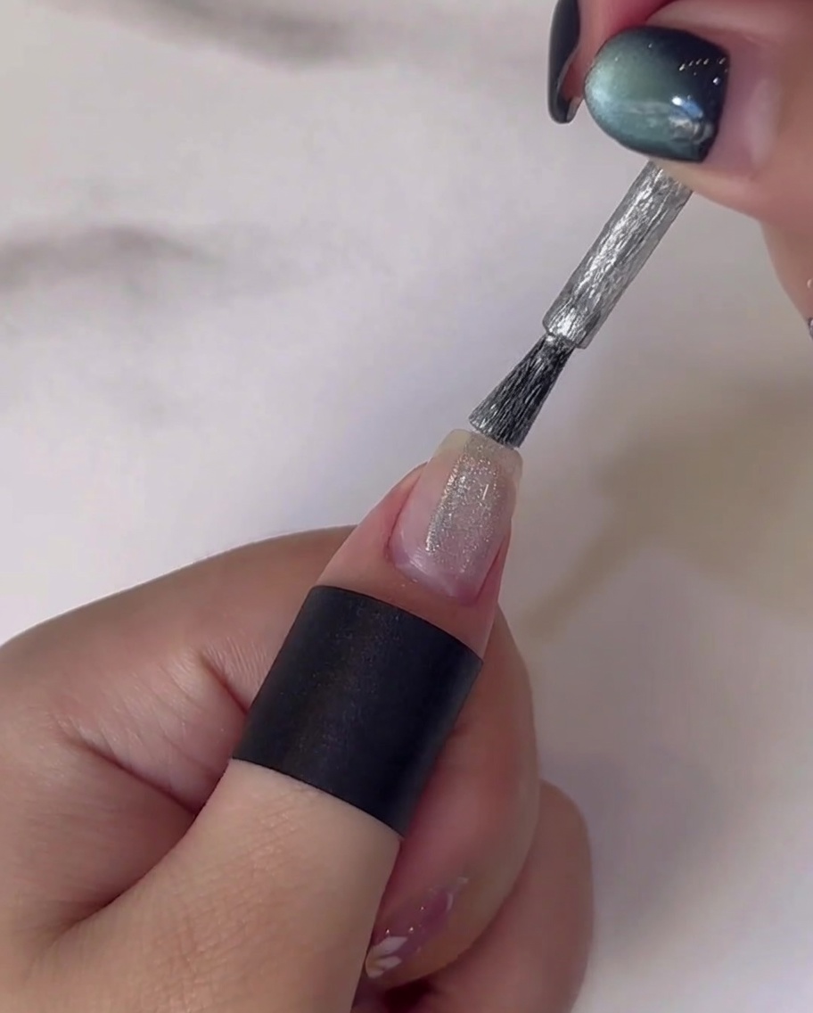 Un dedo con tallos y hojas verdes pintadas siendo curado bajo una lámpara UV/LED.