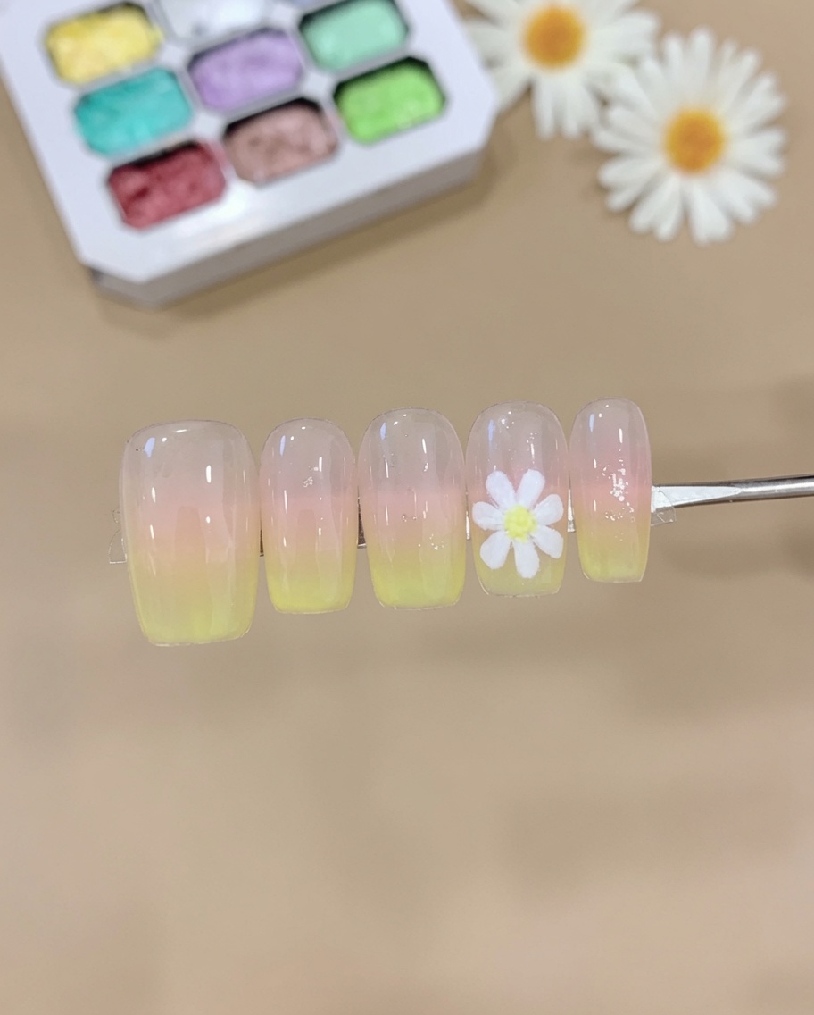 Una esponja aplicando gel rosa y amarillo sobre una uña, creando un degradado ombré suave.