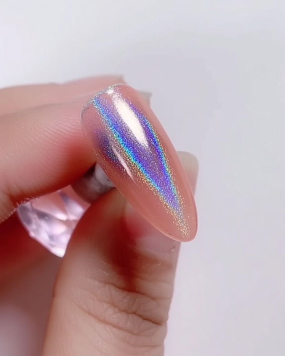 Un pincel aplicando un top coat transparente y brillante sobre el polvo láser iridiscente en la uña.