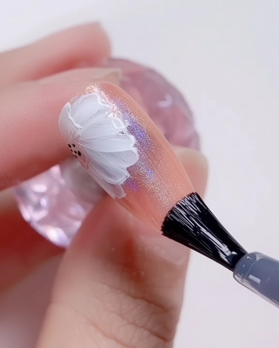 Un pincel aplicando un top coat transparente y brillante final sobre un diseño de uñas de margaritas terminado.