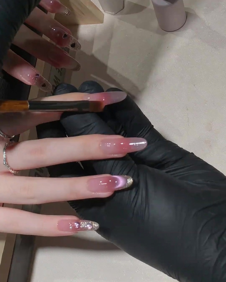 Un pincel plano pequeño siendo usado para arrastrar suavemente el gel rosa hacia arriba en la uña para un efecto degradado.