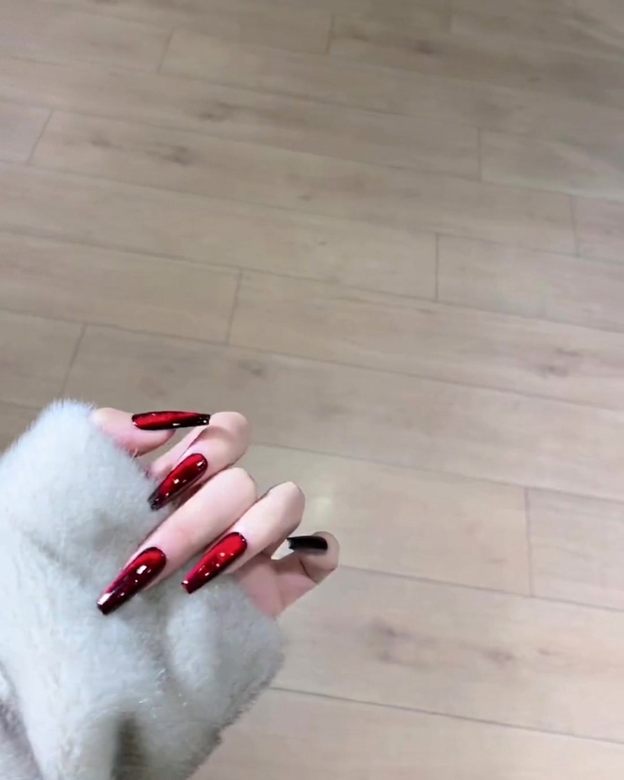 Un pincel aplicando una capa suave de esmalte en gel negro sobre toda la superficie de una uña de longitud natural.